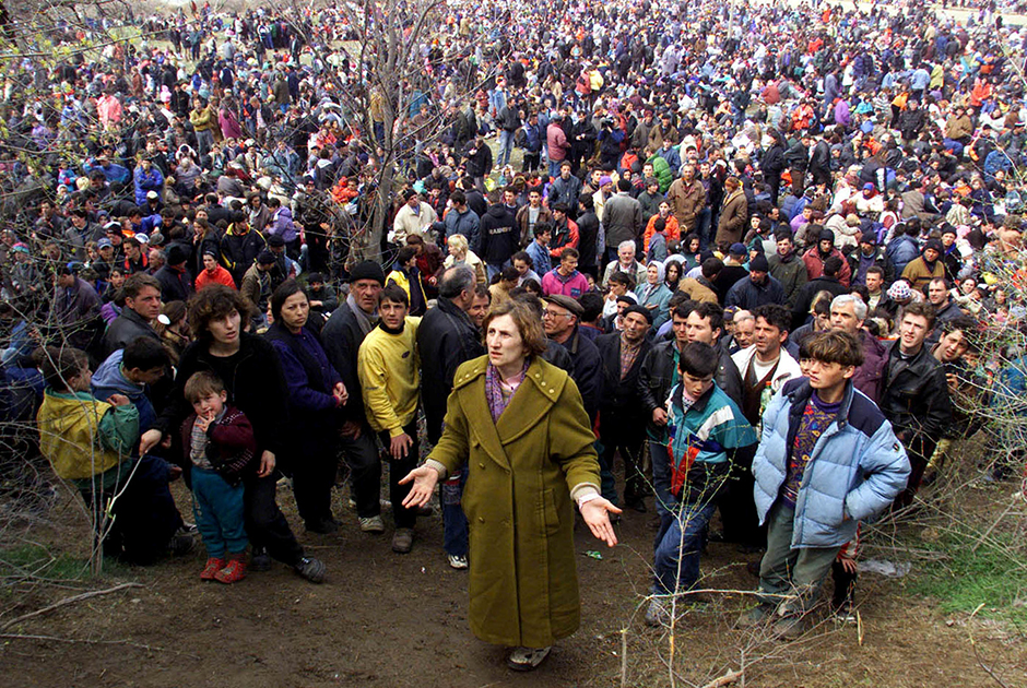 Женщина из Косово стоит перед более чем 10 тысячами этнических албанских беженцев и умоляет македонских полицейских впустить ее в Македонию из буферной зоны на рубеже Югославии и Македонии. 1 апреля 1999 года.