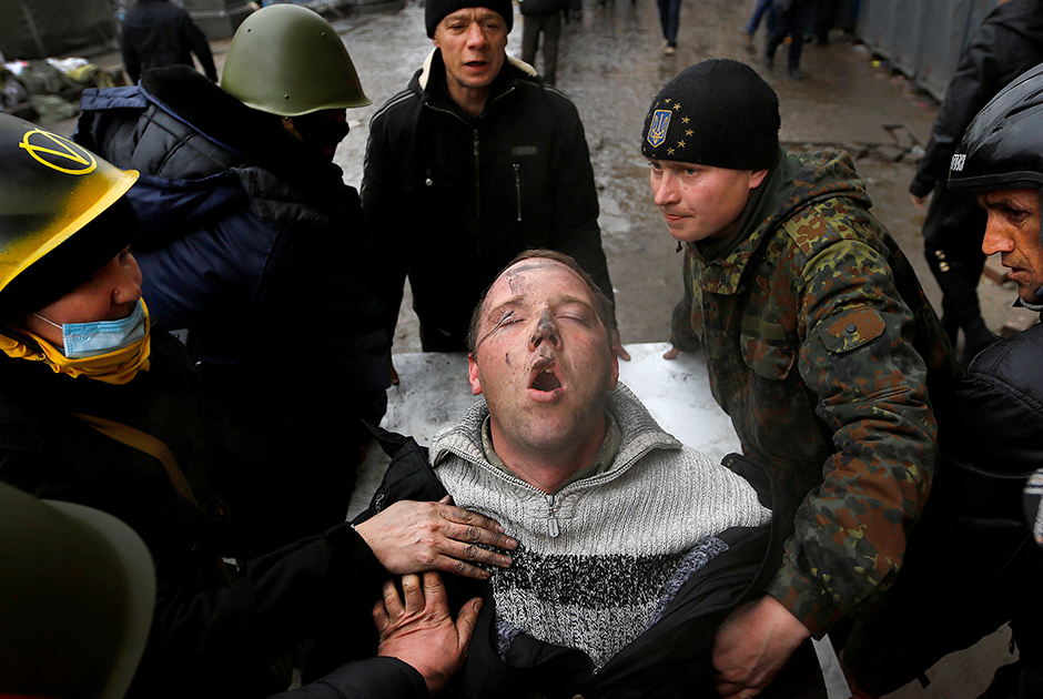 Протестующие против произвола правительства на площади Независимости в Киеве несут раненого единомышленника: он пострадал в столкновении с местными силовиками и еле дышит. 20 февраля 2014 года.