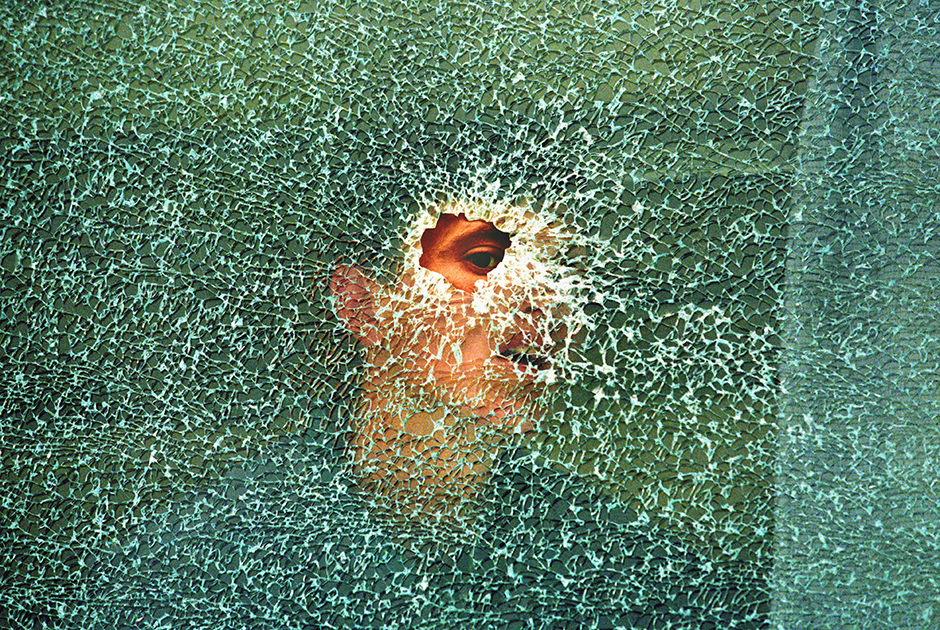 Житель албанской деревни смотрит через пулевое отверстие в окне автобуса. Машина была уничтожена в ходе ожесточенных боев между сербскими силами и этническими албанскими сепаратистами. 11 мая 1998 года, деревня Лапусник в 20 километрах к юго-западу от Приштины.