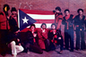 Значительная часть гангстеров банды Warlords была из Пуэрто-Рико. На этом фото 1979 года они позируют в красно-черных свитерах банды с флагом родного острова напротив стены школы Роберто Клименте, в которой многие из них учились. 