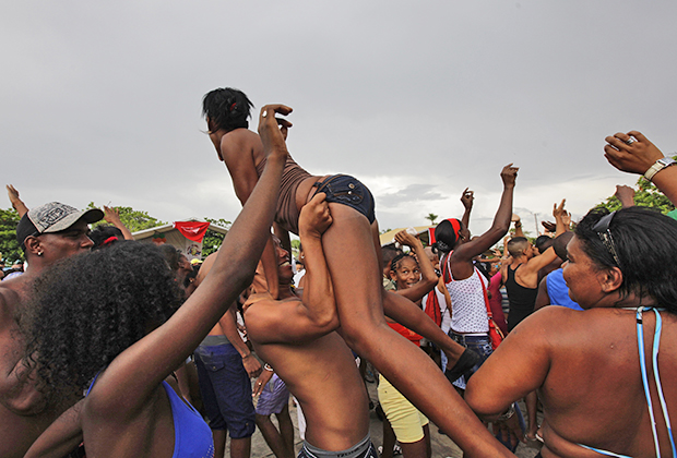 Девушка танцует с прикрепленными к ее бикини упаковками презервативов во время вечеринки в честь открытия ЛГБТ-пляжа в Гаване.