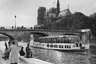 В 1954 году, когда был сделан этот снимок, Нотр-Дам де Пари, как и в наши дни, был обязательной для посещения достопримечательностью, к которой стремилось множество туристов. Они огибали остров Сите в речном трамвайчике, идущем по Сене, фотографировали его с набережной и просто любовались древним собором.