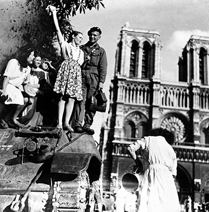 Молодая парижанка празднует освобождение города на броне британского танка напротив Нотр-Дам де Пари.
