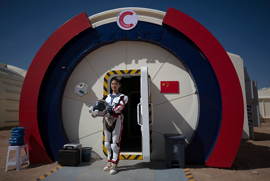 Гид проекта C-Space позирует на входе в шлюзовую камеру марсианской станции, одетая в скафандр, который гипотетически может использоваться в китайской марсианской программе.  