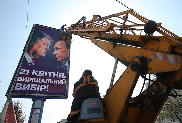 Рабочие монтируют агитационный плакат кандидата в президенты Украины Петра Порошенко на одной из улиц в Киеве