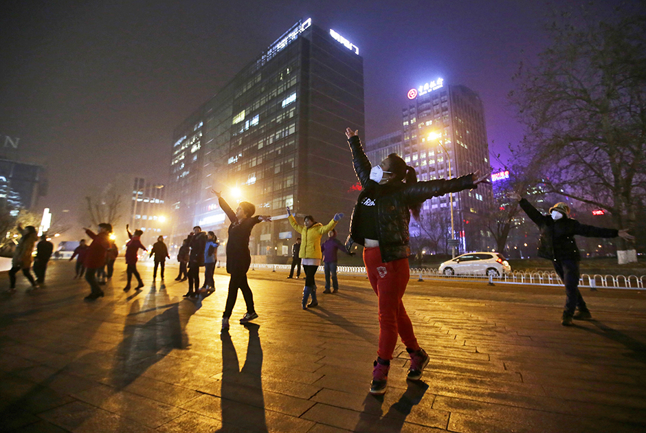 Пекинский смог не мешает упражнениям на улице. Женщины в масках ежедневно занимаются танцами прямо на улице столицы.  