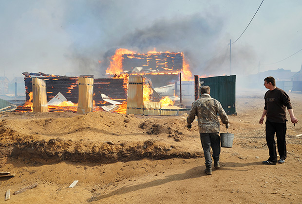Добровольцы тушат лесной пожар, который из-за сильного ветра подобрался к жилым домам.