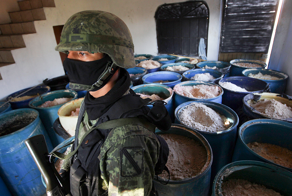 Мексиканский солдат на фоне бочек с 15 тоннами изъятого метамфетамина