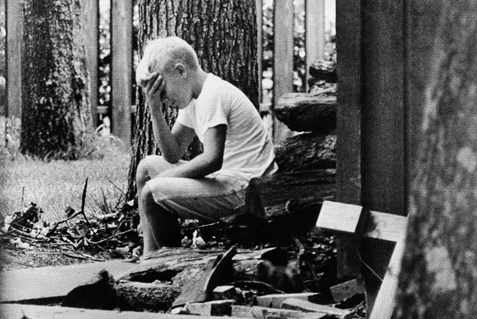 10-летний Энди Олдрин, сын пилота лунного модуля, сидит на стопке дров на заднем дворе дома, пока остальные члены семьи следят по телевизору за Apollo 11.