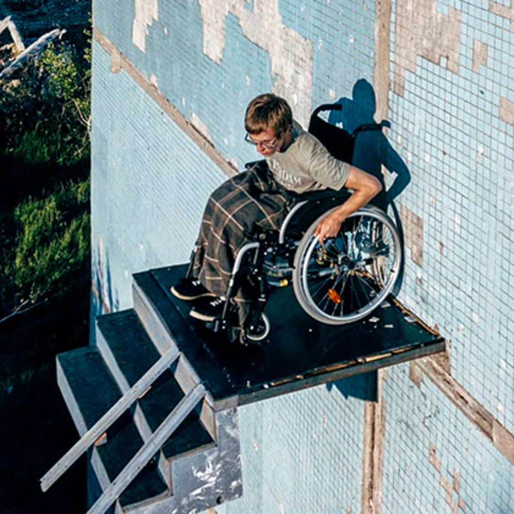 Инвалид колясочник на стене дома