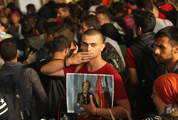 Мигрант из Сирии с портретом Меркель в 2015 году