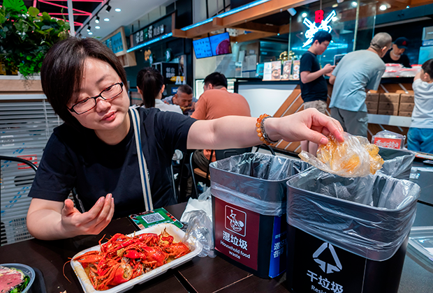 Китай. Шанхай. Местная жительница сортирует отходы во время обеда в городском кафе