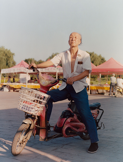Пожилой китаец за рулем электромотоцикла. Снимок сделан в Пинъяо, единственном средневековом городе Китая, полностью сохранившем свой исторический архитектурный облик. У китайцев популярны велосипеды, мопеды, скутеры и мотоциклы. Обладатели разных транспортных средств зачастую передвигаются вместе с автомобилями по проезжей части, а не по выделенным дорожкам.