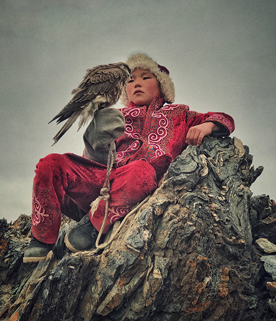«В провинции Баян-Улгий на западе Монголии соколиная охота считается традиционным занятием, которое передается из поколения в поколение. Мальчик начинает обучение уже в 11 лет, и маленький Баха не стал исключением. На фото он как раз только начинает путь со своим соколом».

