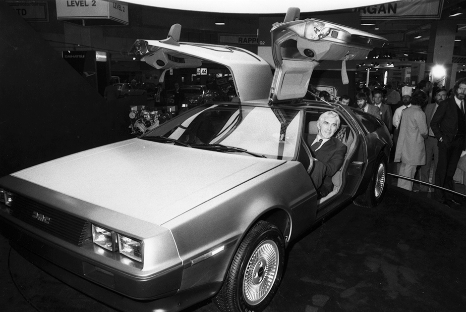 Джон Делореан сидит в DMC-12 на выставке в Лондоне, 1 октября 1981 года. И американцам, и англичанам он представлял свою машину, как отечественную.
