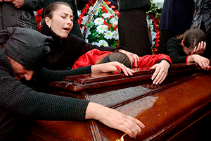 BESLAN, RUSSIA - SEPTEMBER 6: Family and friends of those killed in the school hostage crisis cry over the coffin of a loved one during a mass funeral in the rain September 6, 2004 in Beslan, southern Russia. More than 350 people died after Chechen militant hostage-takers and Russian forces began a firefight that ended violently for more than 1200 held captive inside the school for three days. (Photo by Scott Peterson/Getty Images)