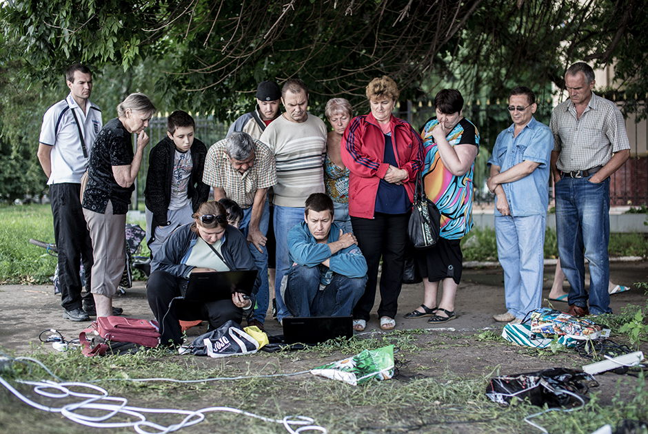 Жители Славянска смотрят новости на ноутбуках возле одной из немногочисленных точек, где есть электропитание. Уже несколько недель большая часть Славянска остается без электричества и водоснабжения. Июнь 2014 года
