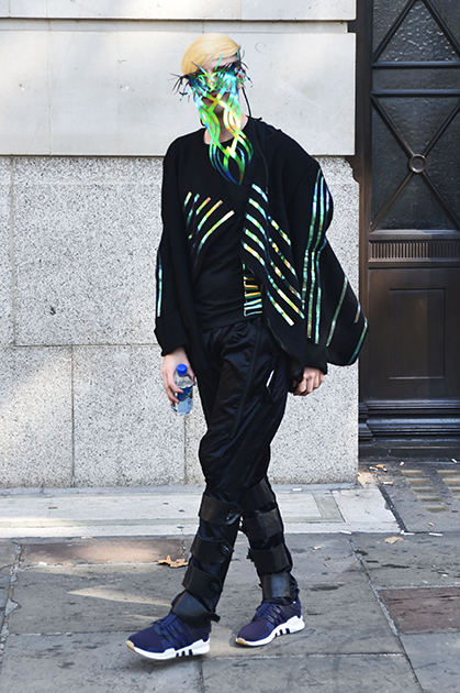 Молодой человек вырезал из бумаги маску в тон полоскам на своей деконструктивистской куртке. Получилось довольно интересно, но для Лондонской недели моды недостаточно вызывающе.