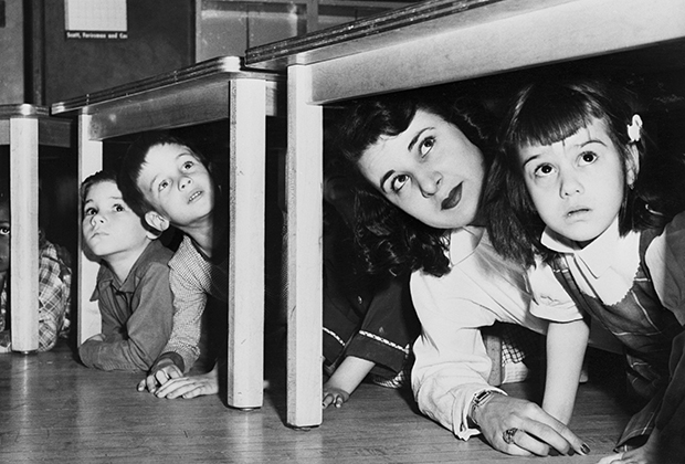 Дети с воспитательницей прячутся под столами после сигнала тревоги