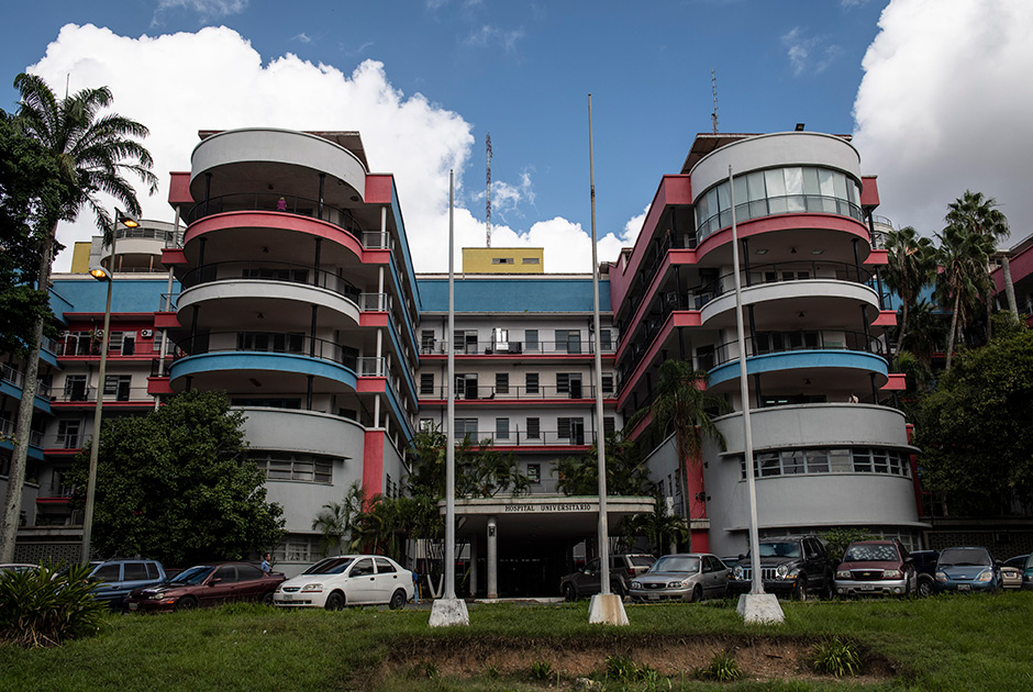 Университетская больница в Каракасе располагается в необычном здании, возведенном по инициативе Елеасара Лопеса Контрераса — президента Венесуэлы в 1935-1941 годах. Внешний облик здания придумал Карлос Рауль Вильянуэва. В 1956-м госпиталь официально открыли.В феврале 2019-го ужасные условия пребывания пациентов в больнице раскрыл телеканал CBC. Журналисты выяснили, что в здании частично отсутствует электричество, из одиннадцати лифтов работает один — с перебоями, больных нечем кормить и зачастую нечем лечить — лекарства в дефиците. Сотрудникам больницы нерегулярно выплачивают зарплаты, а некоторым из них приходится ночевать на работе, чтобы не тратиться на проезд в общественном транспорте.