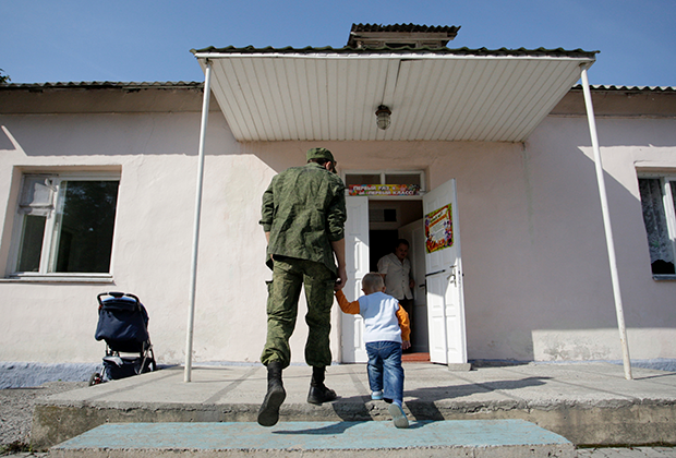 Житель Донецка ведет ребенка в школу, 2015 год