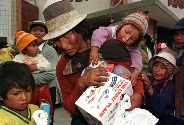 Женщина-представитель коренного населения несет со своими детьми подарки на Рождество бедным детям столицы Ла-Пас
