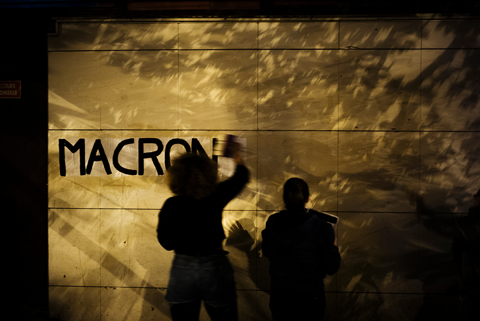 Майя клеит надпись с именем президента Франции Эммануэля Макрона на юге Парижа.
