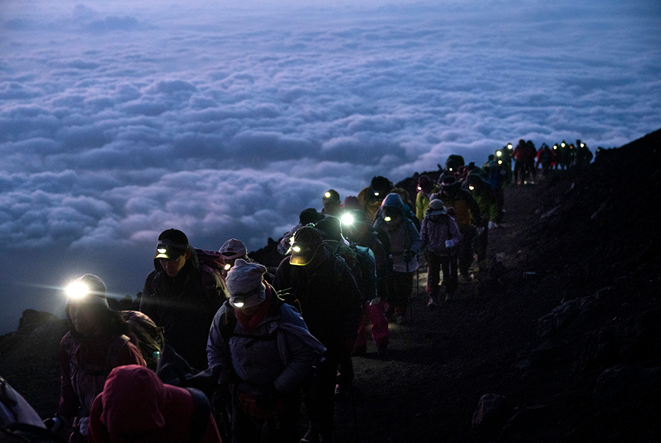 Альпинисты над слоем облаков взбираются на вершину японской горы Фудзи, чтобы посмотреть на восход Солнца. Фудзияма — самая высокая точка во всей Японии, и насладиться видом с нее мечтают все настоящие туристы. Из-за обилия желающих на горе нередко скапливаются предрассветные пробки.
