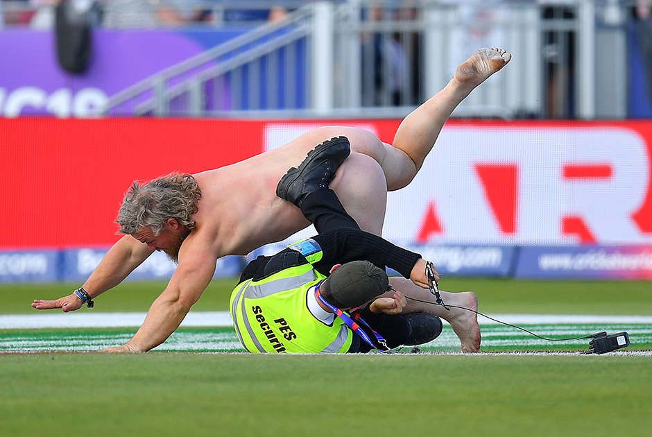 Стюард пытается задержать фаната, выбежавшего на поле во время матча группового этапа чемпионата мира по крикету между Новой Зеландией и Англией.  Внимание, спойлер: любителя побегать в неглиже в конце концов схватили.