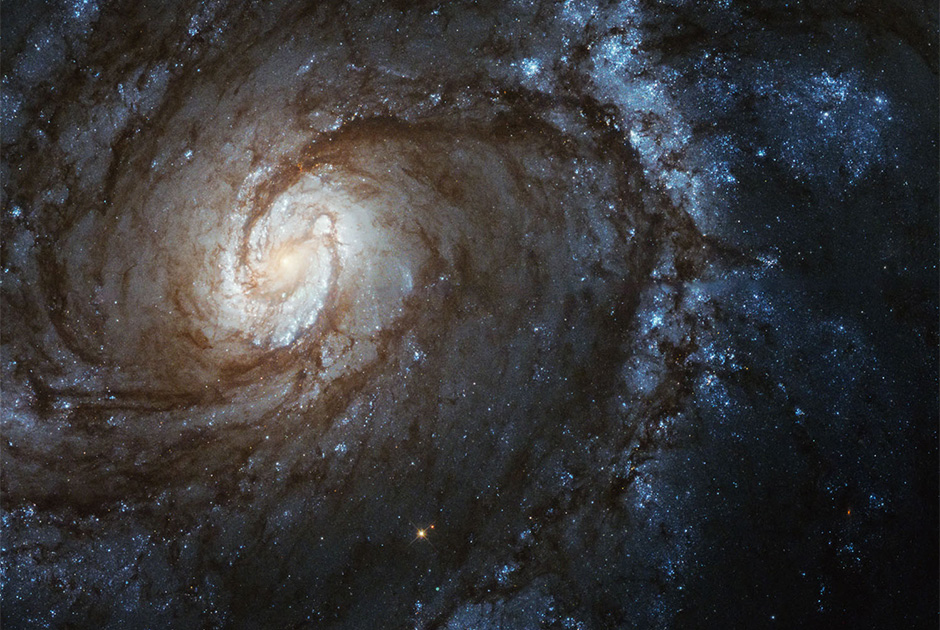 Этот снимок спиральной галактики М100 снят на «Широкоугольную камеру 3», установленную на телескопе «Хаббл» в 2009 году. Яркий желтый цвет в центре М100 обусловлен свечением старых звезд, а по краям галактики находятся молодые синие звезды. М100 находится на расстоянии 55 миллионов световых лет от Солнца и содержит более 100 миллиардов звезд. 
