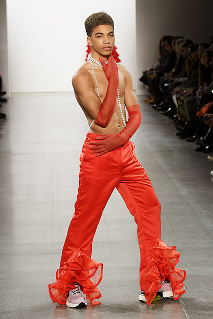 Обычно на публике топлес появляется Эмили Ратаковски, однако на дебютном показе 22-летней дизайнерши Тии Адеолы (Tia Adeola) свой накачанный торс показала совсем другая модель. Он прошелся по подиуму в брюках модного в 2020 году ярко-оранжевого цвета с оборками на вырезах штанин и в кроссовках в стиле колор-блок. Незамысловатый образ дополняли прозрачные перчатки того же цвета и длинные бусы.