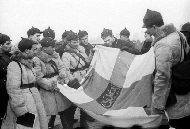 Группа советских командиров и бойцов осматривает отбитое у финнов знамя шюцкора (военизированной организации-ополчения), 1939 год. Фотограф Э. Хайкин