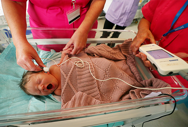 Медсестры проверяют слух новорожденного в больнице при Университете Милтон-Кинса. Милтон-Кинс, Великобритания