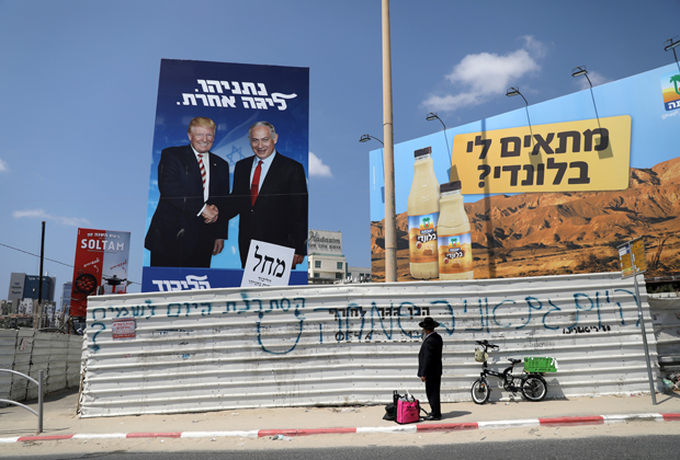 Ортодоксальный еврей возле плаката партии «Ликуд» с изображением Нетаньяху и Трампа