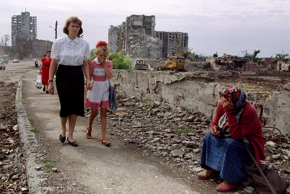 Жители Грозного проходят мимо пожилой женщины, просящей милостыню. Чеченские боевики согласились сложить оружие после полугода вооруженного противостояния. 22 июня 1995 года