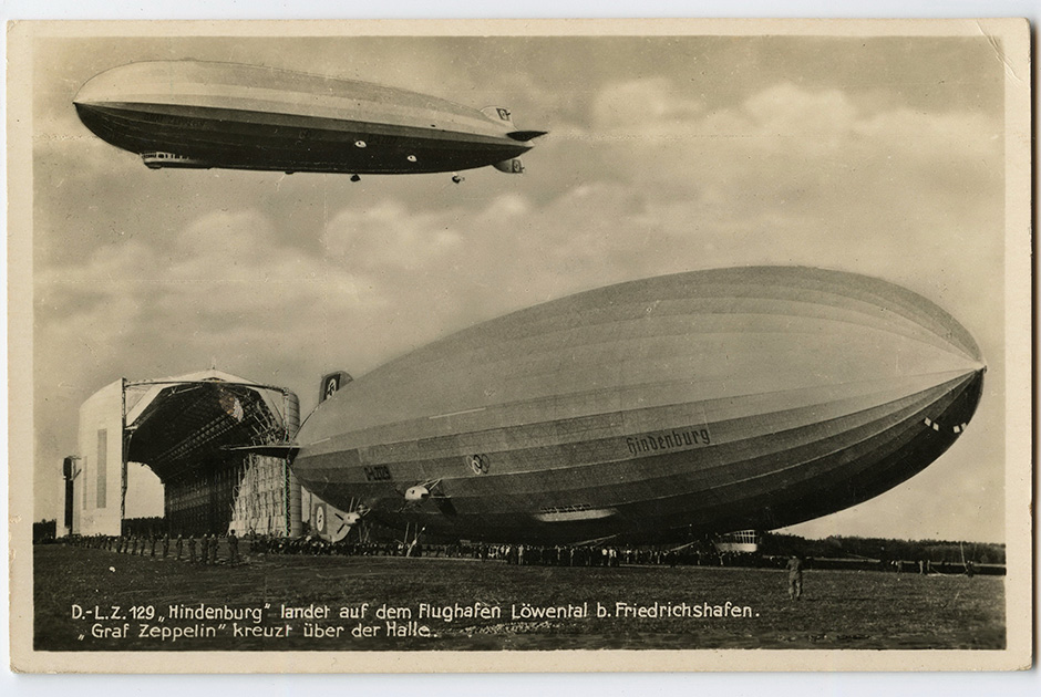 Дирижабли Hindenburg (LZ-129) и Graf Zeppelin (LZ-127, в воздухе). «Гинденбург» принимал участие в открытии Олимпийских игр в Берлине в 1936 году, поэтому у него на борту изображены олимпийские кольца. Гибель «Гинденбурга» 6 мая 1937 года фактически определит будущее воздухоплавания. Немецкая открытка 1936 года