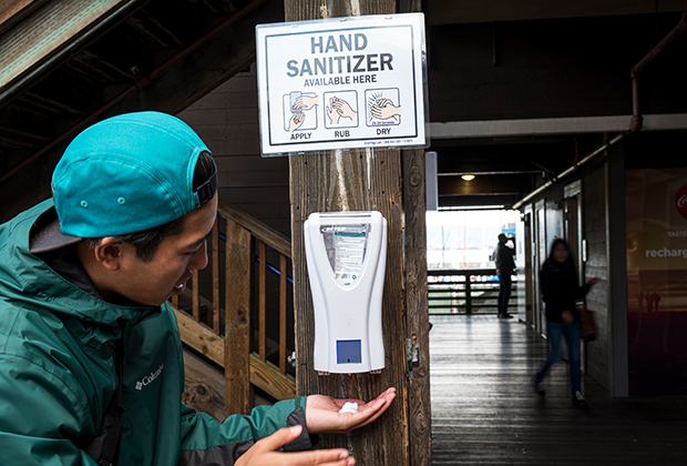 Житель Сан-Франциско очищает руки санитайзером