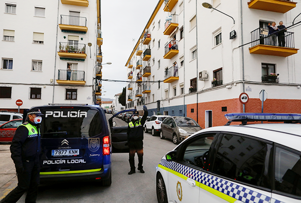 Офицер полиции приветствует людей, собравшихся на балконах в городе Ронда, Испания