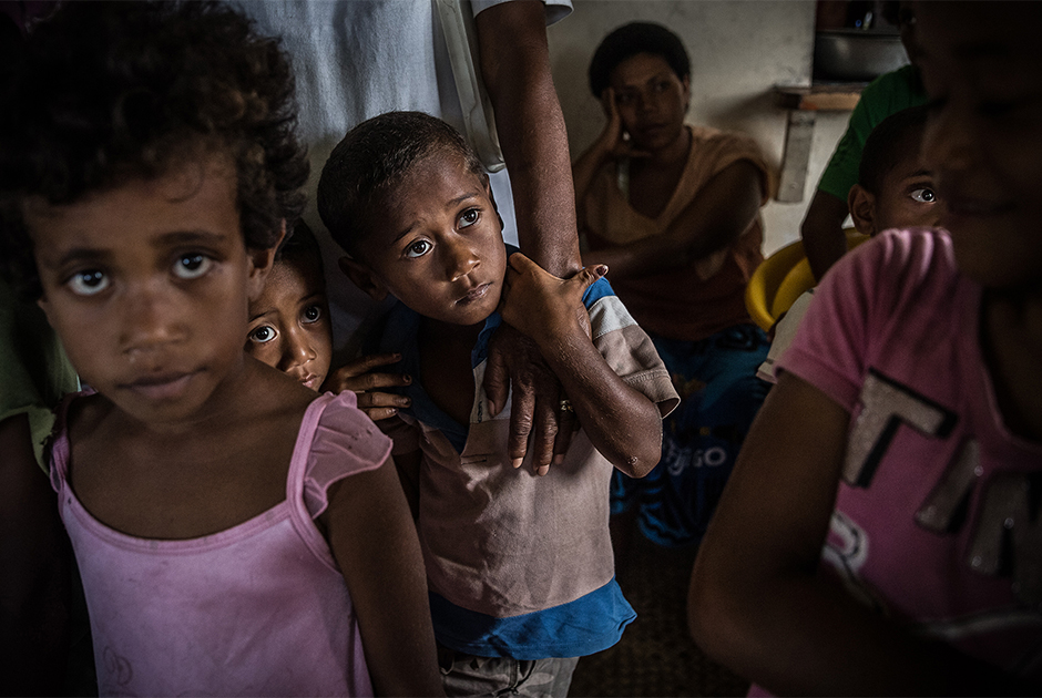 Дети из деревни Канацеа на острове Тавеуни (Фиджи) вместе с родителями ждут поставки продовольствия. Большая часть домов в их деревне полностью разрушена циклоном «Уинстон». Многие жители укрылись в эвакуационных центрах или спали под открытым небом.

