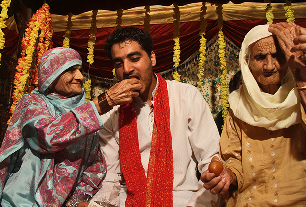 Родственники угощают жениха традиционными сладостями в день церемонии нанесения хны. Равалпинди, Пакистан, 2013 год