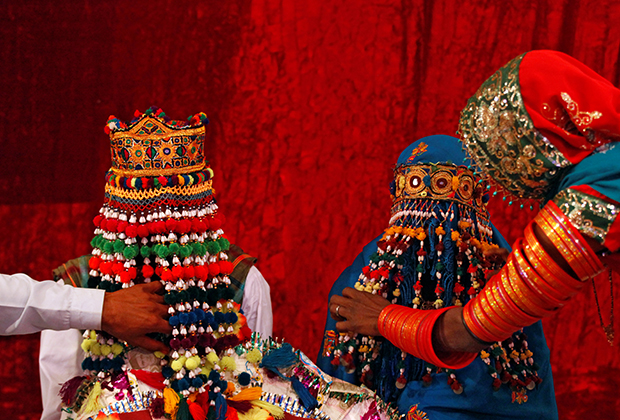 Жених и невеста в традиционных тюрбанах ручной работы во время церемонии бракосочетания, организованной индуистским советом в Карачи, Пакистан, 2018 год