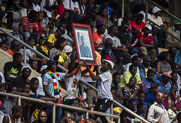 Люди с портретом Роберта Мугабе на Национальном спортивном стадионе в Хараре в день похорон президента