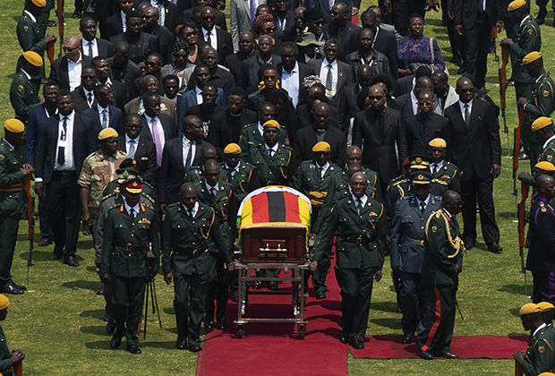 Гроб с телом Роберта Мугабе, накрытый государственным флагом, сопровождают члены семьи и высокопоставленные лица