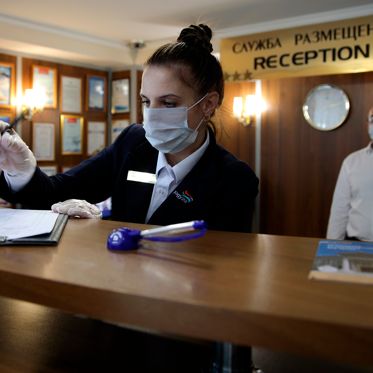 Можно заселиться в гостиницу по военному билету. Фото сотрудницы. Сфера гостеприимства. Пандемия. Регистрация гостей в отеле.