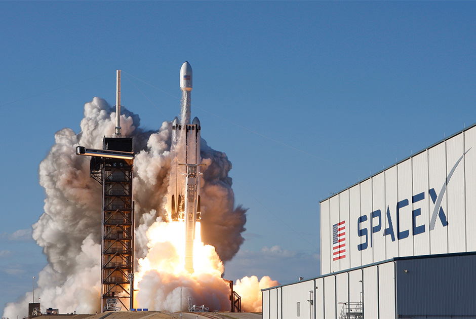 Первый пуск единственной действующей в мире сверхтяжелой ракеты Falcon Heavy состоялся 6 февраля 2018 года. Носитель вывел на гелиоцентрическую орбиту автомобиль Tesla Roadster. Конструктивно первая ступень Falcon Heavy состоит из центрального блока и пары боковых ускорителей, представляющих собой модернизированные первые ступени тяжелой Falcon 9. Заявляемая грузоподъемность носителя на низкую околоземную орбиту составляет 64 тонны, на околомарсианскую — 17 тонн.