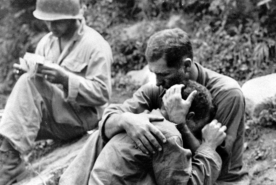 Американский пехотинец плачет на плече товарища после гибели своего друга. В это время санитар (на снимке — слева) занимается документальным оформлением боевых потерь. 28 августа 1950 года.