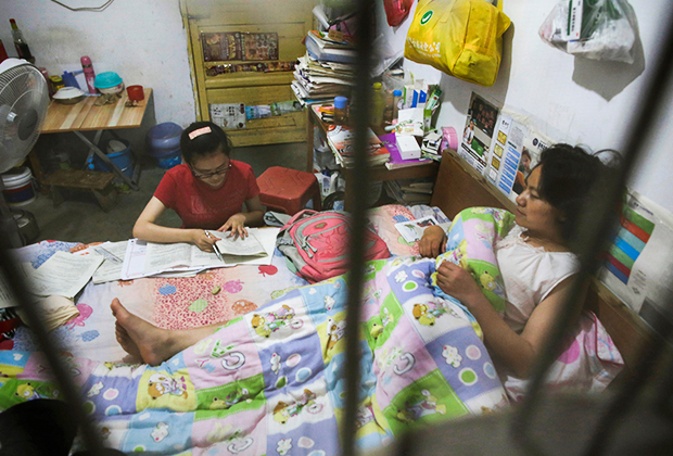Школьница делает домашнее задание на кровати, где лежит ее мать, в Маочантане