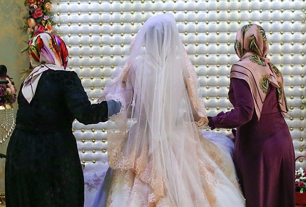 Невесту ведут на место, где она будет стоять все время празднования чеченской свадьбы