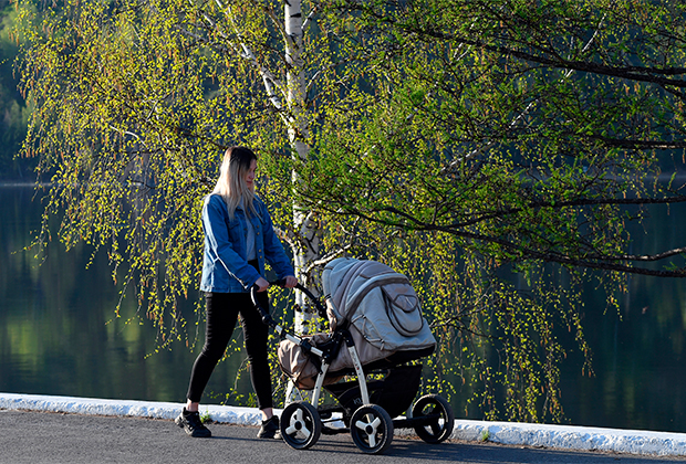 Женщина с детской коляской гуляет по набережной Енисея в городе Дивногорске Красноярского края