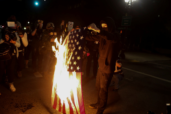 Участник протестов конца сентября в Портленде жжет американский флаг